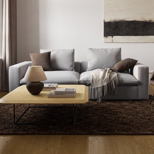 Extra stor coh djup ljusgrå soffa miljöbild med brun ull matta och stort soffbord i ek